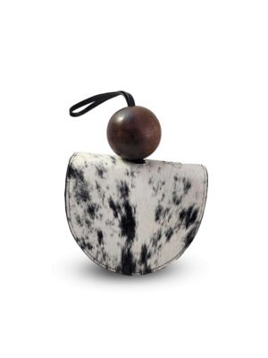 Clutch Wayra artesanal hecho en Perú con cuero de pelo natural blanco y negro, diseño circular estructurado y esfera de madera sostenible.